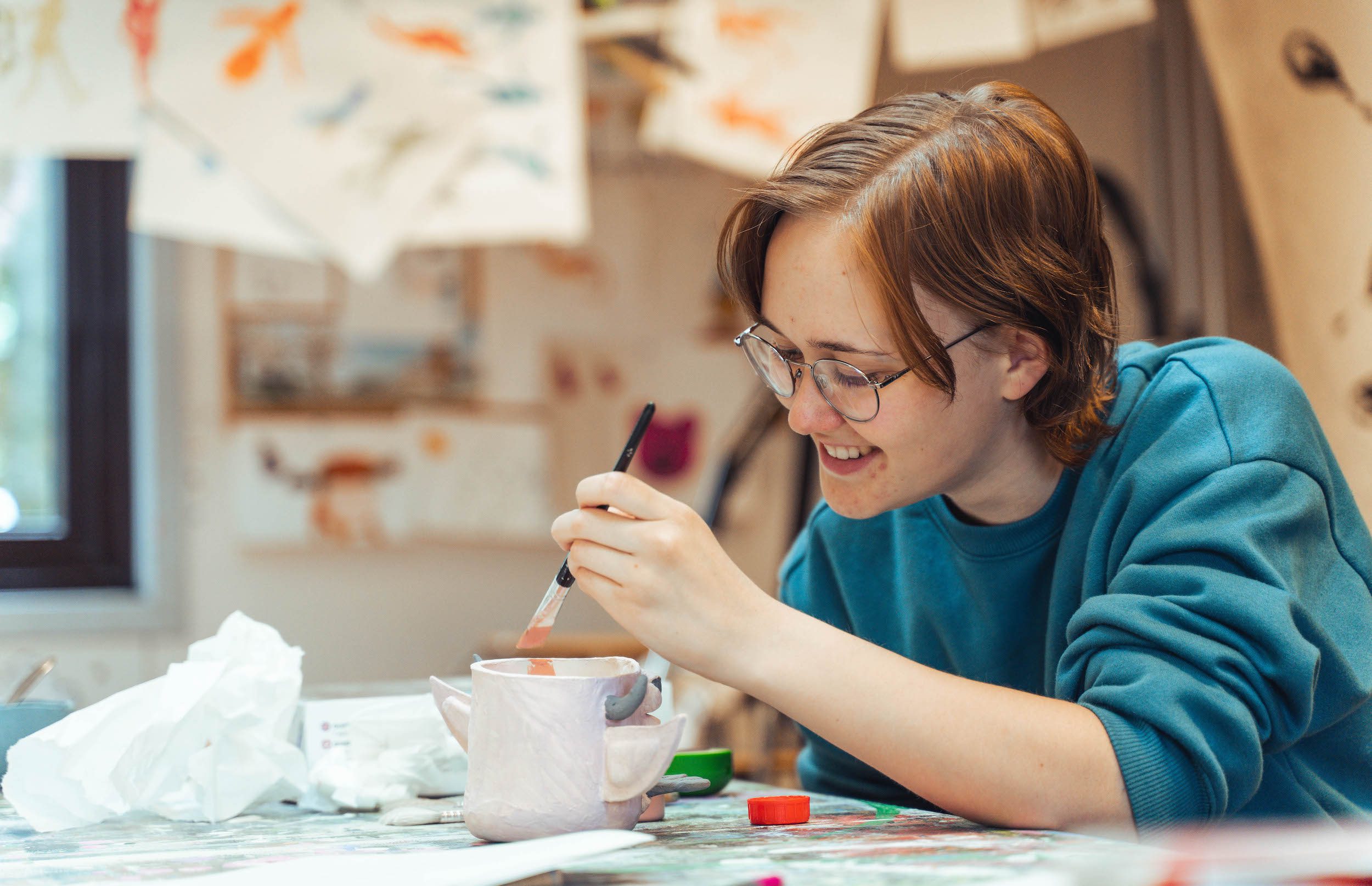 Pige arbejder med keramik og maling på efterskolens kunstlinje